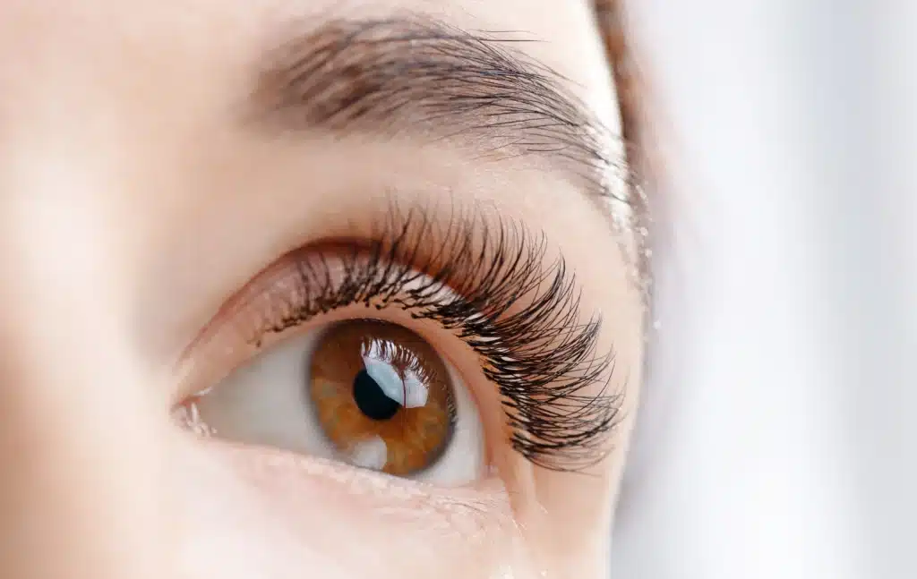 Extensions de Cils : Sublimez votre Regard avec Volume Gros plan d'un œil brun avec des extensions de cils noires, volumineuses et recourbées pour un regard intense.
