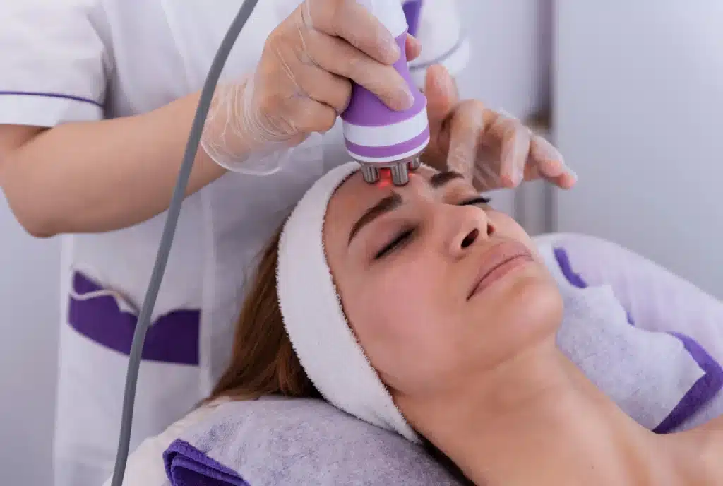Soin Radiofréquence Visage : Rajeunissement de la Peau Soin du visage par radiofréquence et lumière rouge appliqué par une esthéticienne sur une cliente détendue.